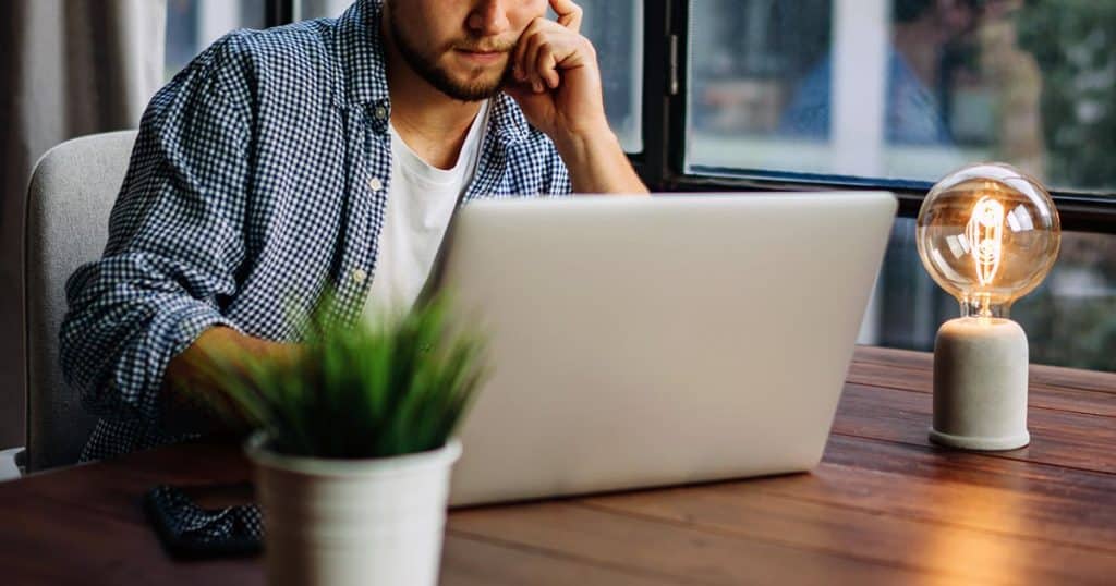 Man working at laptop adjacent to bright globe