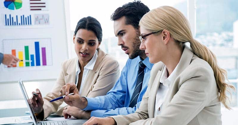 Group of 3 professionals sitting around a laptop