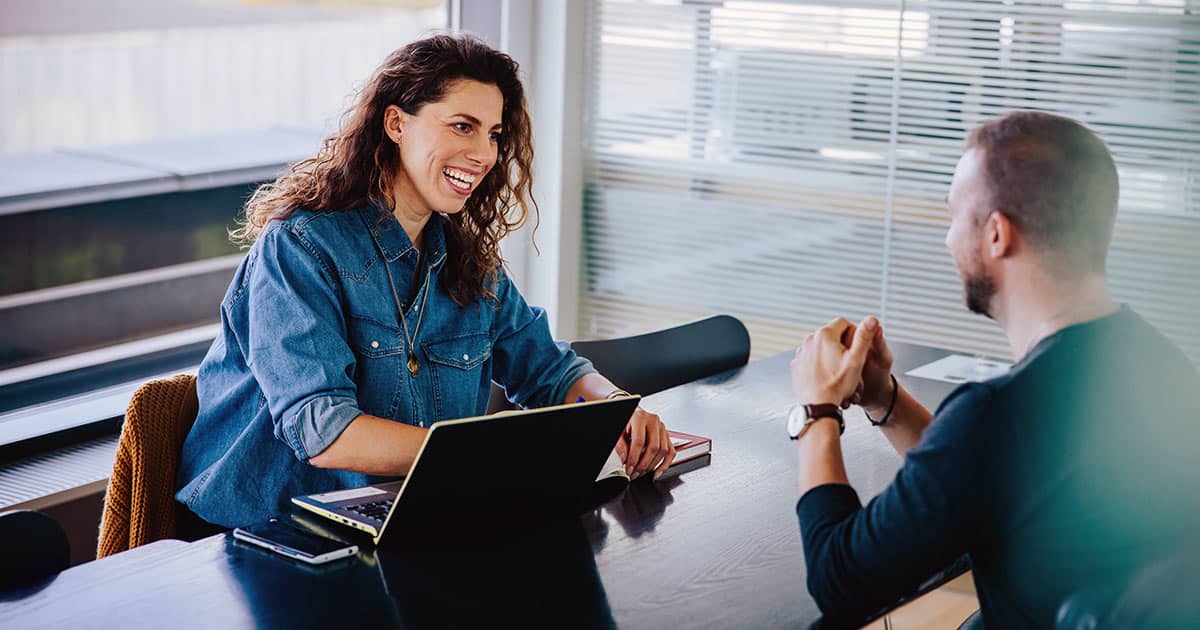 Smiling woman interviewing man in her office